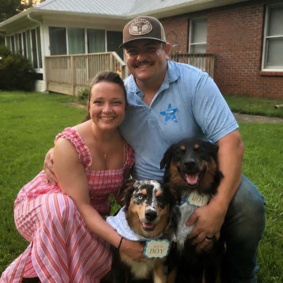 A family smiling with their grown Shepherd Farms dogs outside their home
