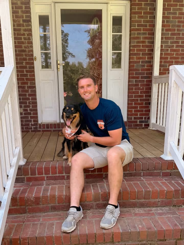 A man sitting on porch steps with his dog