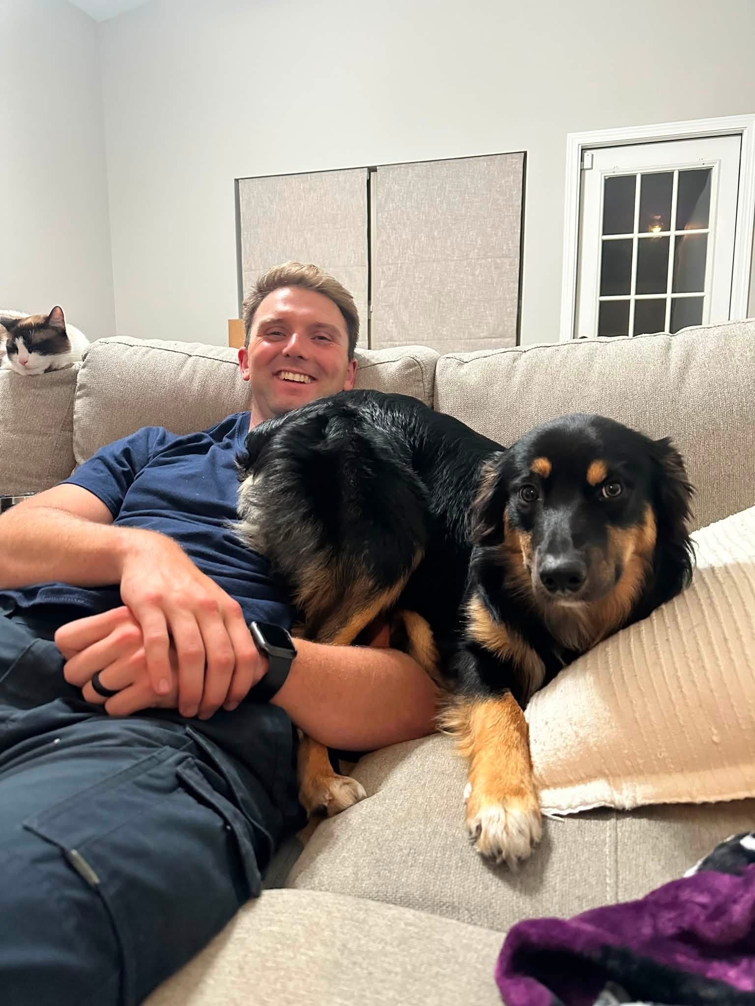 A man relaxing on a couch with his grown dogs