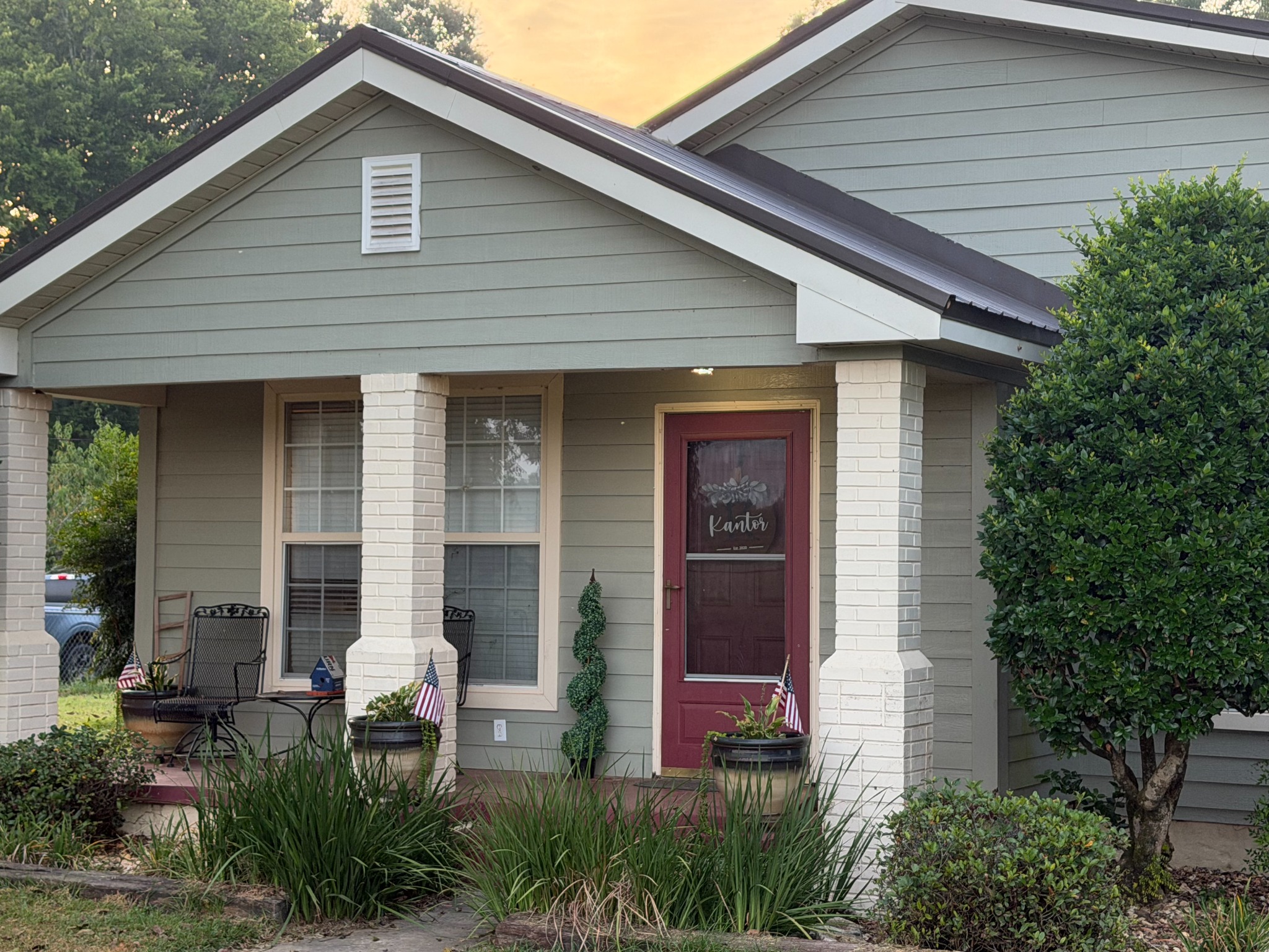 The front porch at Shepherd Farms with green plants and small American flags in the planters